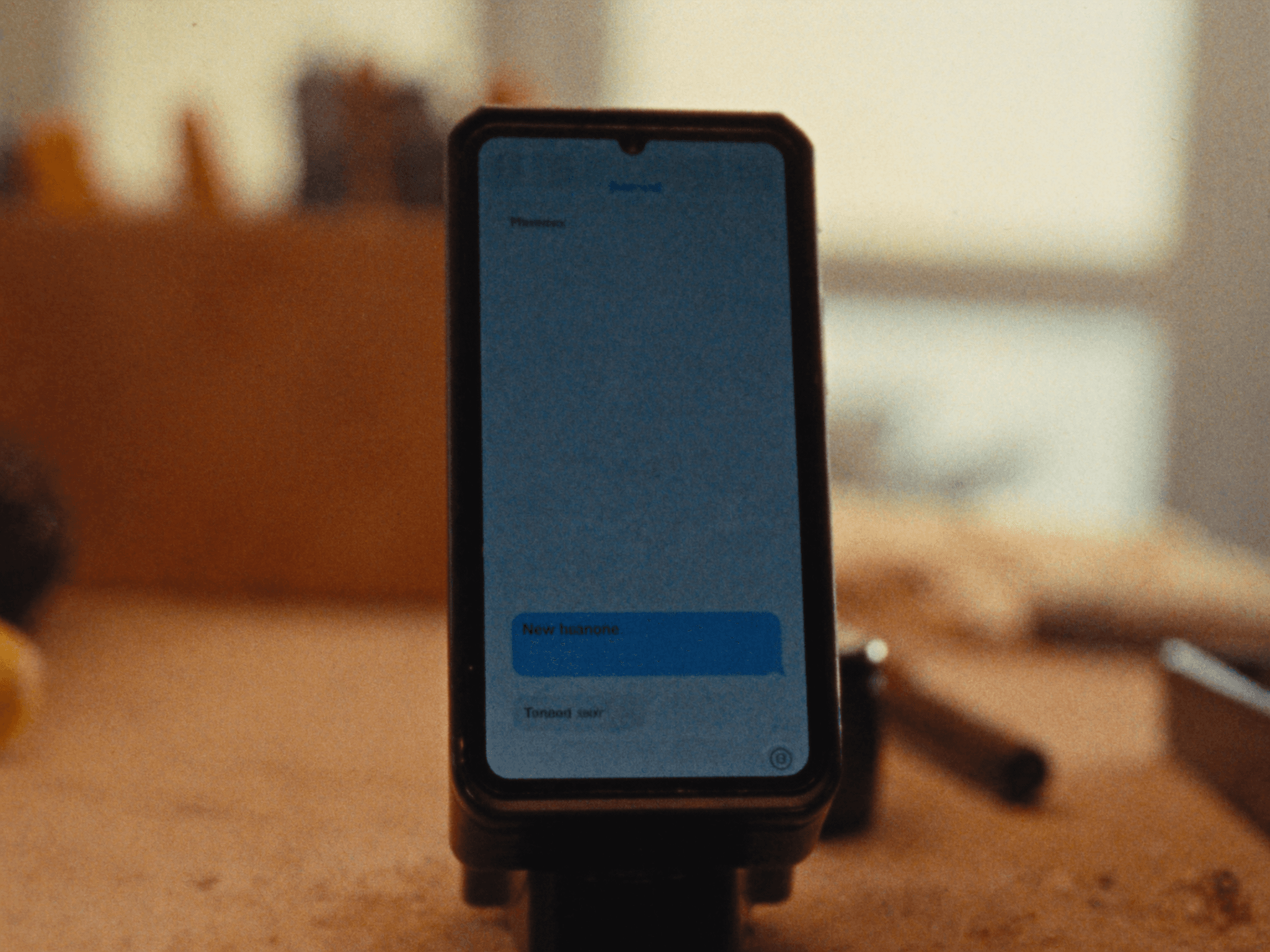 A phone lighting up with a message on a workbench