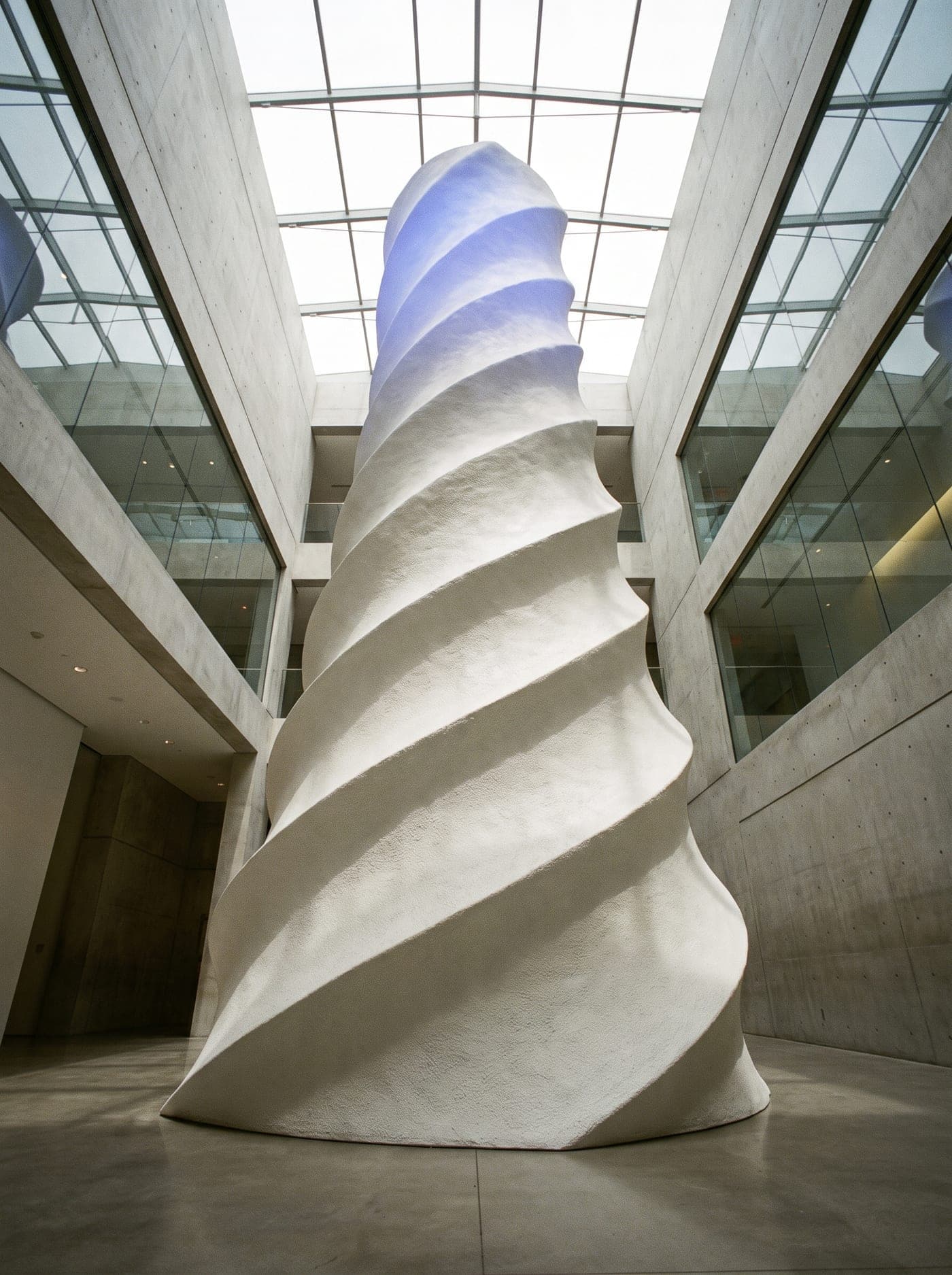 A completed porcelain tower crowned with ultramarine light in a bright atrium